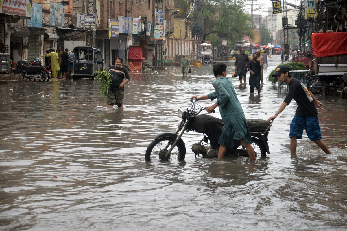 epa13147327 People wade through a flooded road during heavy monsoon rain in Hyderabad, Pakistan, 02 August 2026. Pakistan's disaster management and weather authorities warned that a new monsoon s ...