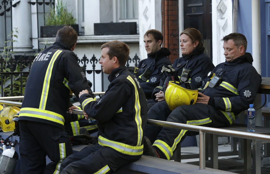 Firefighters wait to start their shift after a massive fire raged in a 27-floor high-rise apartment building in London, Wednesday, June 14, 2017. London&#039;s Metropolitan Police said a number of peo ...