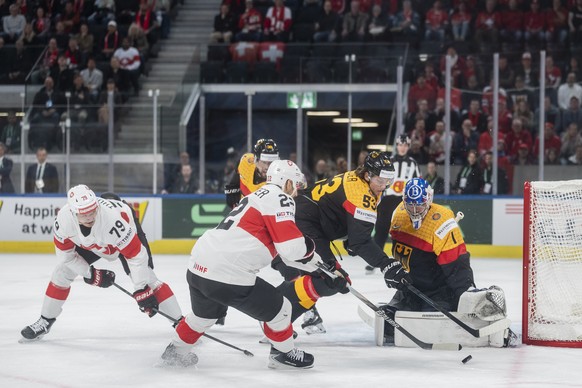 Switzerland's Calvin Thurkauf and Nino Niederreiter, from left, challenge Germany's goaltender Jonas Stettmer and Germany's Moritz Seider, from right, during the 2026 IIHF Men's Ic ...