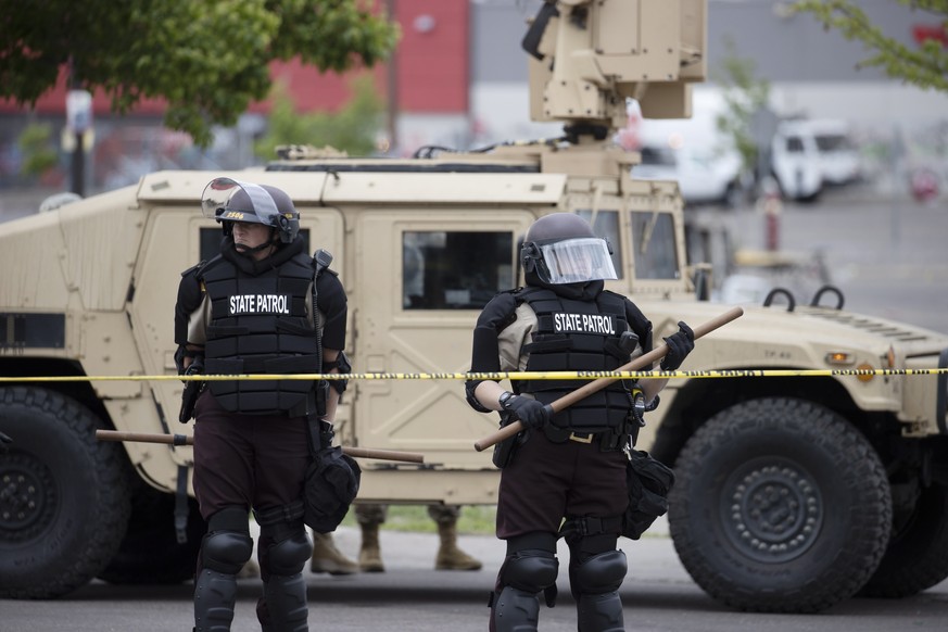 epa08453112 Members of the National Guard and Minnesota State Troopers keep watch as firefighters work in an area of destroyed businesses after a third day of protests over the arrest of George Floyd, ...