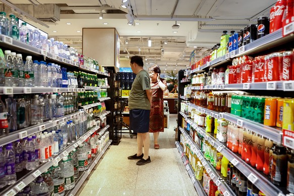 epa10736922 A couple looks at drinks at a supermarket in Beijing, China, July 9, 2023 (released July 10, 2023).  China's inflation fell to zero percent in June, from 0.20 percent in May...