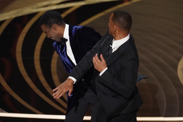 Will Smith, right, hits presenter Chris Rock on stage while presenting the award for best documentary feature at the Oscars on Sunday, March 27, 2022, at the Dolby Theatre in Los Angeles. (AP Photo/Ch ...