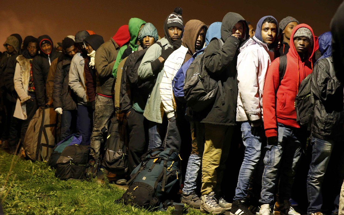 Migrants with their belongings queue as their evacuation and transfer to reception centers in France, and the dismantlement of the camp called the "Jungle" in Calais, France, starts October  ...