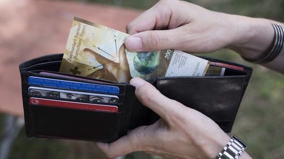 A person takes a 200 Swiss franc bill out of a wallet, pictured in Zurich, Switzerland, on August 23, 2018. (KEYSTONE/Christian Beutler)

Eine Person entnimmt eine 200-Franken-Banknote aus einem Porte ...