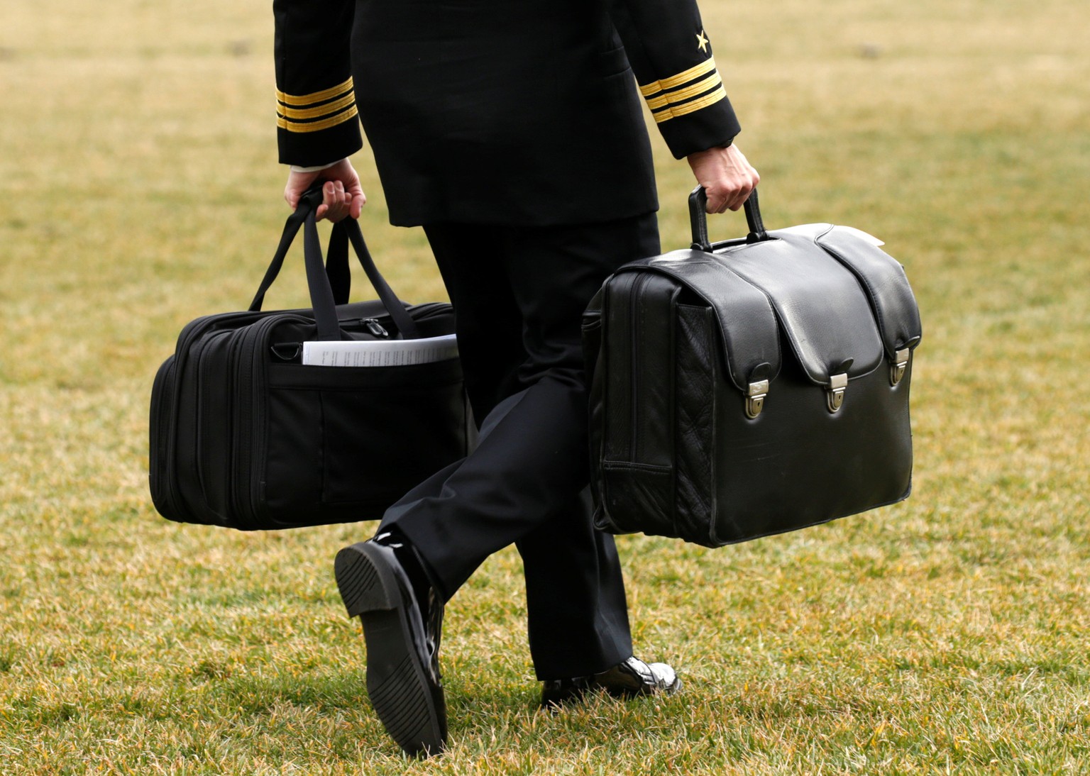 A military aide, carrying the &quot;football&quot; containing launch codes for nuclear weapons, accompanies U.S. President Donald Trump onto Marine One upon Trump&#039;s departure from the White House ...
