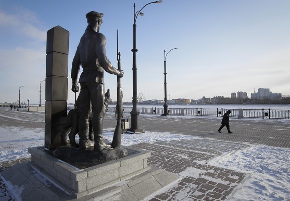 A man walks past a sculpture of a border guard at an embankment of the Amur River being the border between Russia and China in the city of Blagoveshchensk in the far eastern Amur region, Russia, Wedne ...