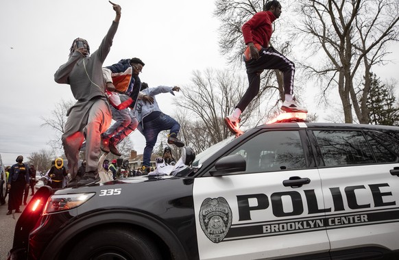 Men jump on police vehicles near the site of a shooting involving a police officer, Sunday, April 11, 2021, in Brooklyn Center, Minn. (Carlos Gonzalez/Star Tribune via AP)