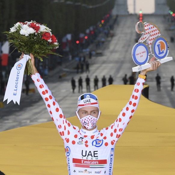 Tour de France winner Slovenia&#039;s Tadej Pogacar, who also won the best climber&#039;s dotted jersey, celebrates on the podium after the twenty-first and last stage of the Tour de France cycling ra ...