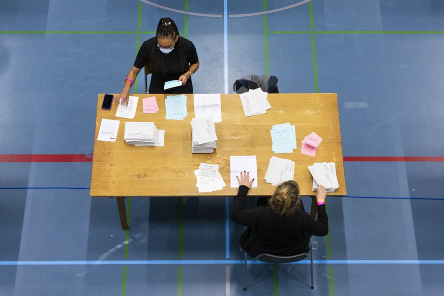 Wahlhelferinnen sortieren die Wahlzettel und Abstimmungszettel der eidgenoessischen Abstimmungen und der Berner Stadtrats- und Gemeinderatswahlen, am Freitag, 27. November 2020 in der Sporthalle Weiss ...