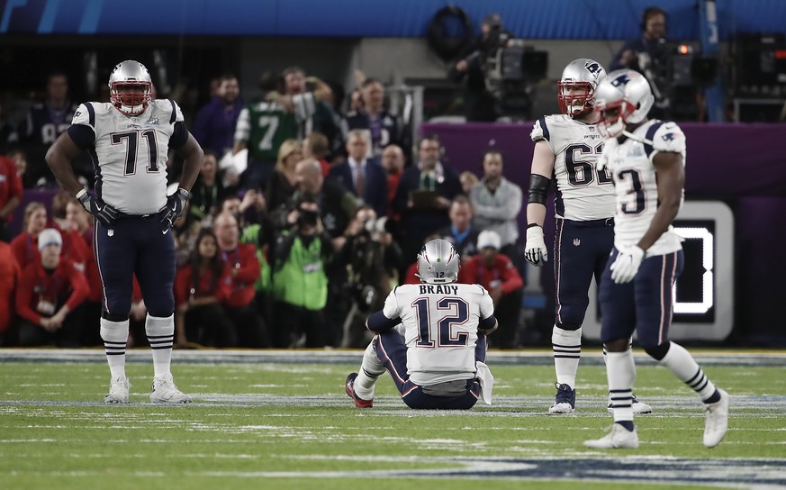 epa06497310 New England Patriots quarterback Tom Brady (C) sits on the field after fumbling the football, while New England Patriots offensive tackle Cameron Fleming (L) and New England Patriots offen ...