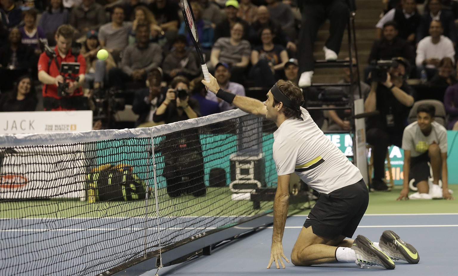 Roger Federer, of Switzerland, hits from his knees as he plays in an exhibition tennis match with partner Bill Gates against Jack Sock and Savannah Guthrie in San Jose, Calif., Monday, March 5, 2018.  ...