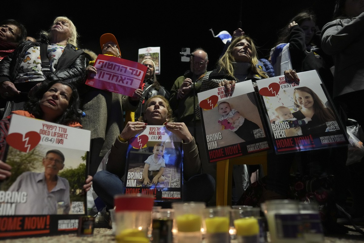 People gather by candles as they hold posters during a vigil in Tel Aviv, Israel, Thursday, Feb. 20, 2025, hours after Hamas militants turned over four bodies to Israel, three of which have been ident ...