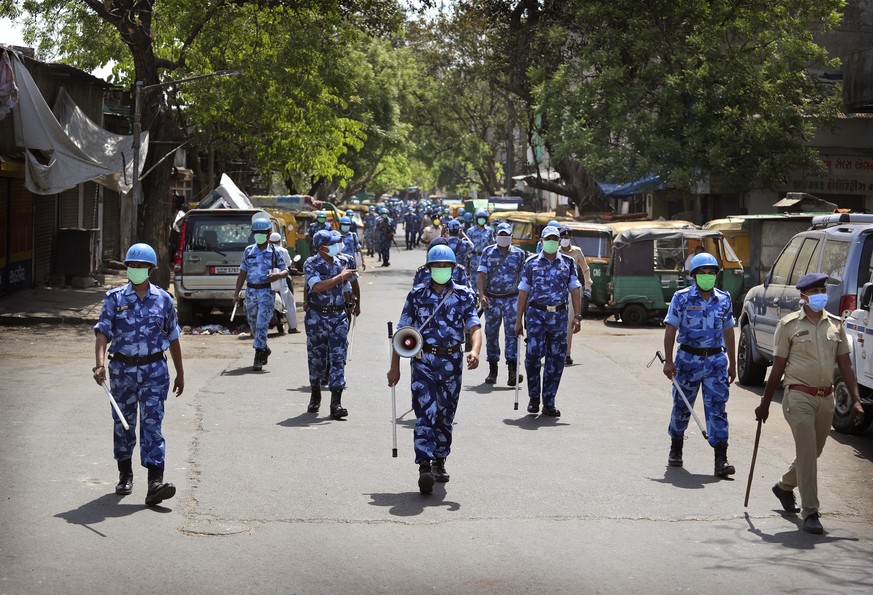 FILE- In this April 11, 2020 file photo, Rapid Action Force (RAF) personnel patrol a street during lockdown to control the spread of the new coronavirus in Ahmedabad, India. India, a bustling country  ...