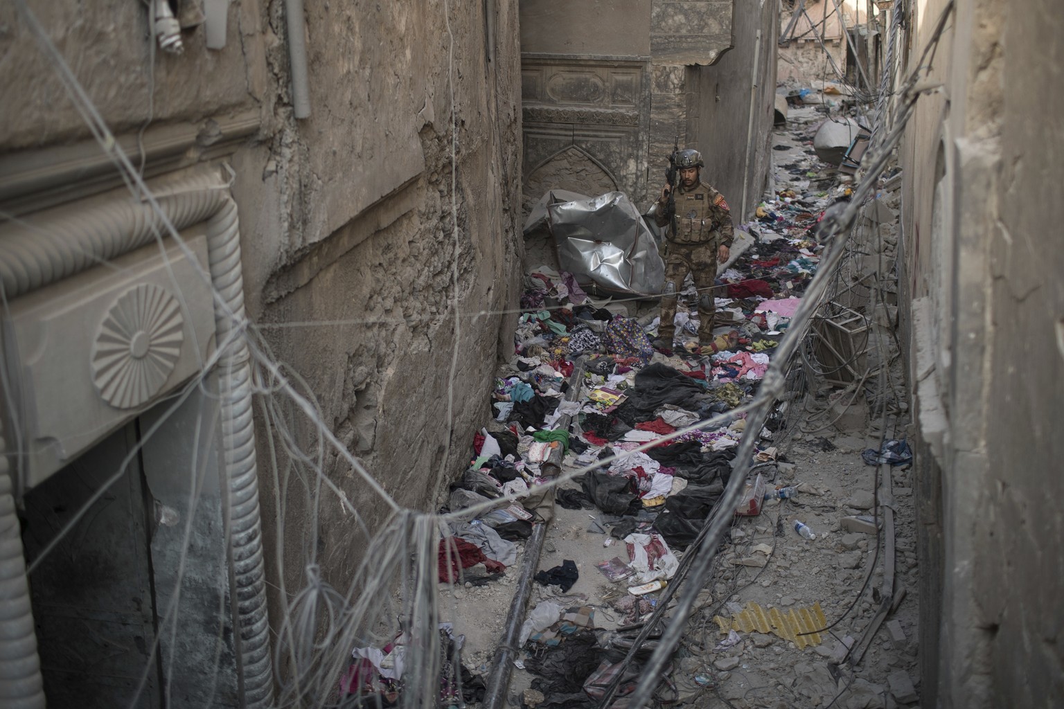 An Iraqi Special Forces soldier walks on clothes left behind by fleeing civilians in an alley as Iraqi forces continue their advance against Islamic State militants in the Old City of Mosul, Iraq, Wed ...
