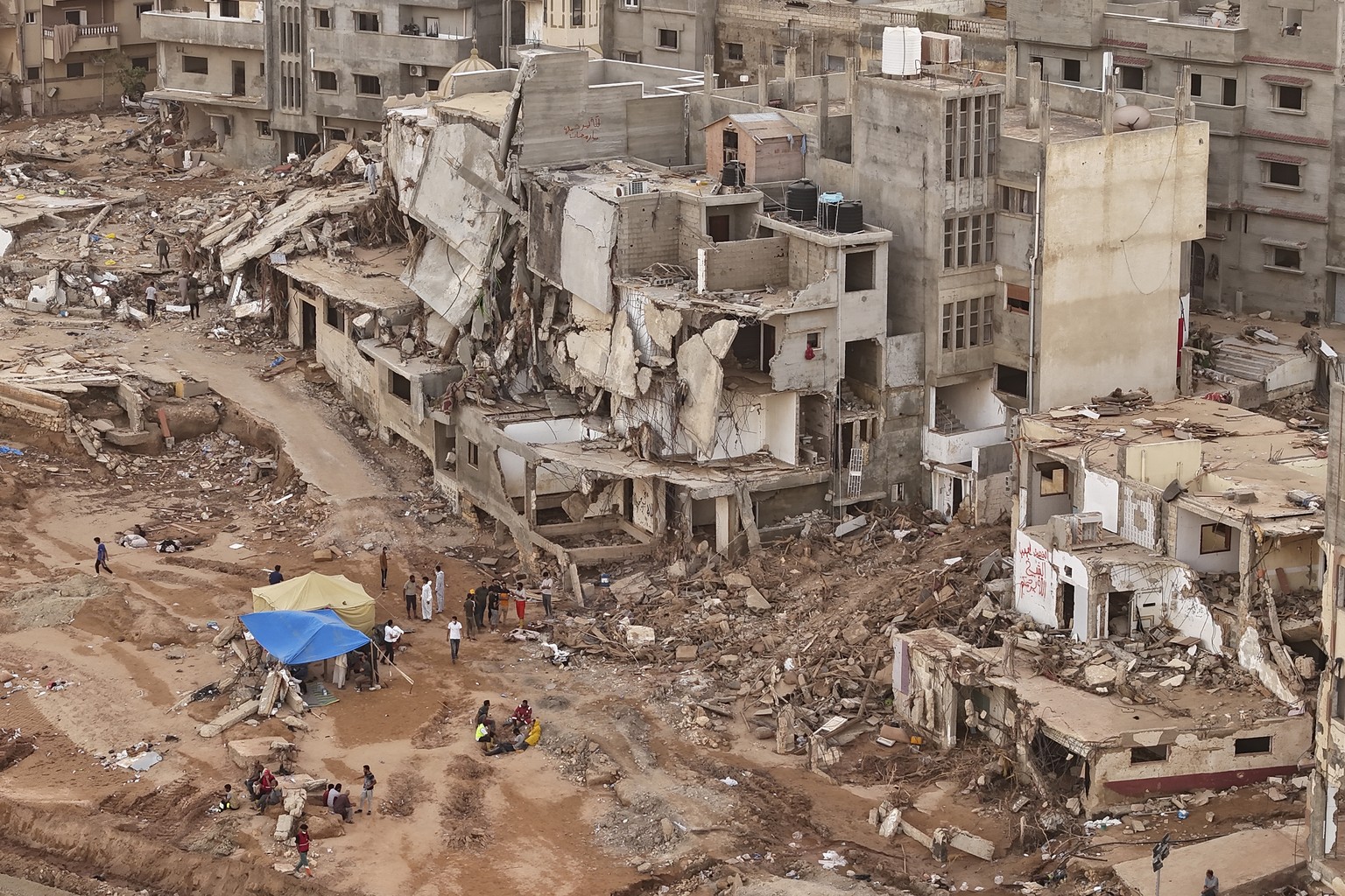 Rescuers and relatives sit in front of collapsed buildings after recent flooding caused by Mediterranean storm Daniel, in Derna, Libya, Monday, Sept. 18, 2023. Derna flood survivor Abdul Salam Anwisi  ...