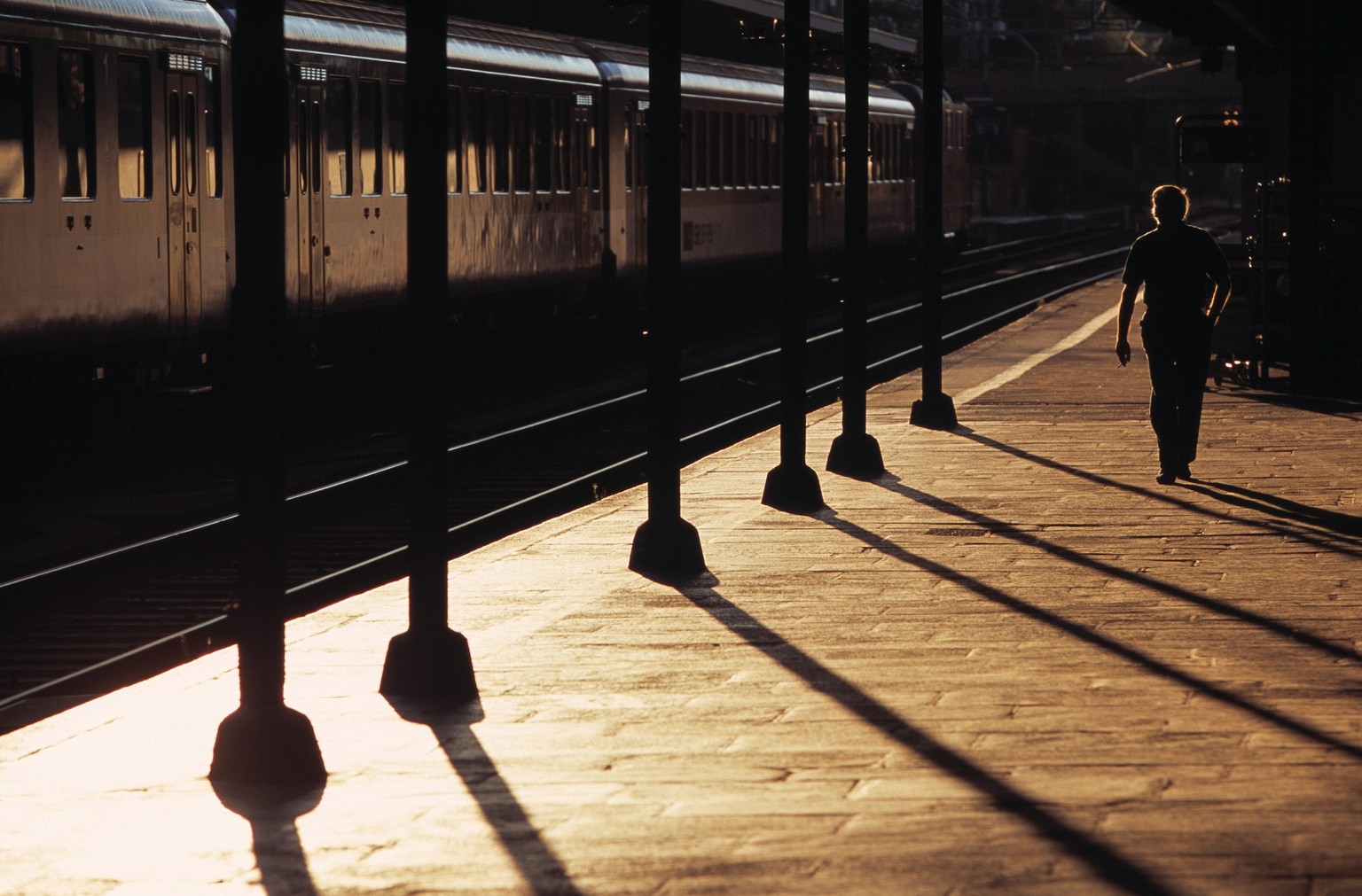 Die tief stehende Sonne zeichnet auf dem Bahnsteig im Bahnhof Locarno am 26. August 2003 lange Schatten. (KEYSTONE/Martin Ruetschi) === , === : DIA]