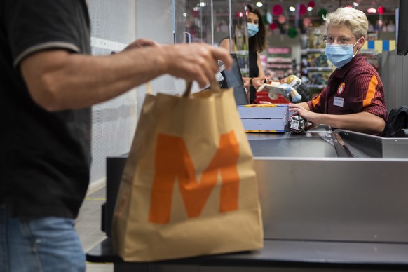 Une personne paie des courses a la caisse a une vendeuse portant un masque sur le visage dans un magasin Migros le mercredi 8 juillet 2020 a Crissier. Les masques sont obligatoires dans les magasins d ...