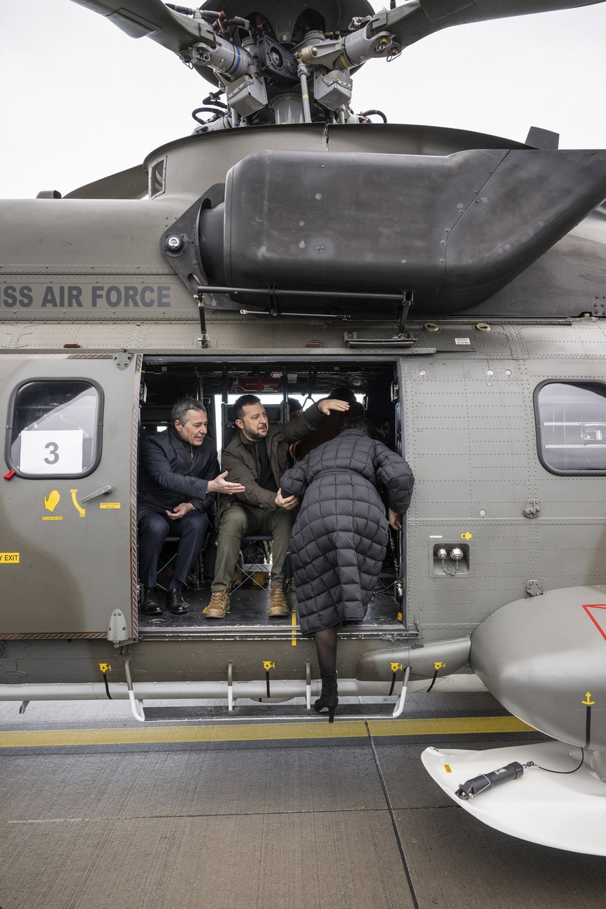 Switzerland's Foreign Minister Federal Councillor Ignazio Cassis, left, and his State guest Volodymyr Zelenskyy, President of Ukraine, center, help a passenger board their Super Puma Helicopter o ...
