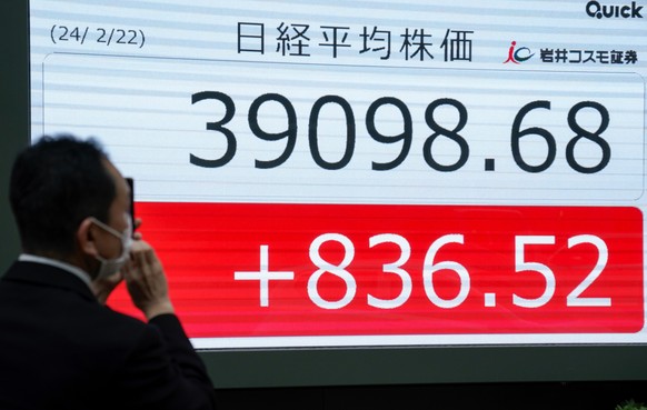 epa11171557 A pedestrian takes a commemorative photo of a display showing the new record high closing of the Nikkei Stock Average in Tokyo, Japan, 22 February 2024. Tokyo&#039;s stock benchmark rose 8 ...