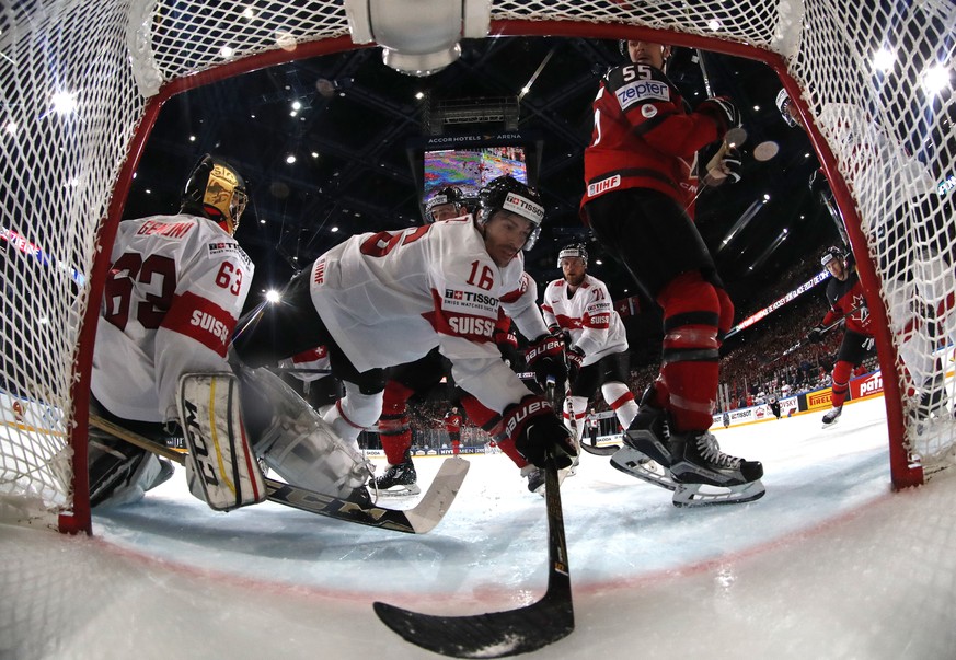 Switzerland&#039;s Raphael Diaz, center, falls over Switzerland&#039;s Leonardo Genoni, left, during the Ice Hockey World Championships group B match between Canada and Switzerland in the AccorHotels  ...