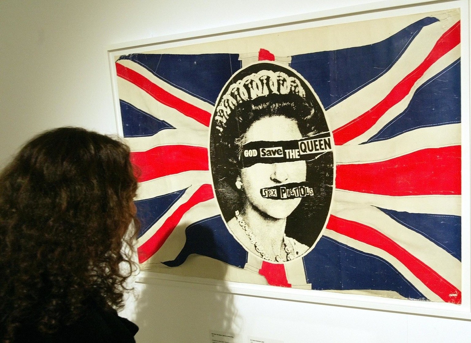 A visitor to the &quot;Punk: A True and Dirty Tale&quot; exhibition in central London looks at one of the most famous images from punk band the Sex Pistols, Wednesday Oct. 6, 2004. The God Save The Qu ...