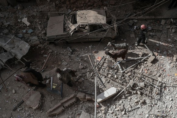 epa06613925 People walk in a damaged area after overnight shelling on Douma, eastern Ghouta, Syria, 19 March 2018. According to reports, at least nine people were killed after forces loyal to the Syri ...