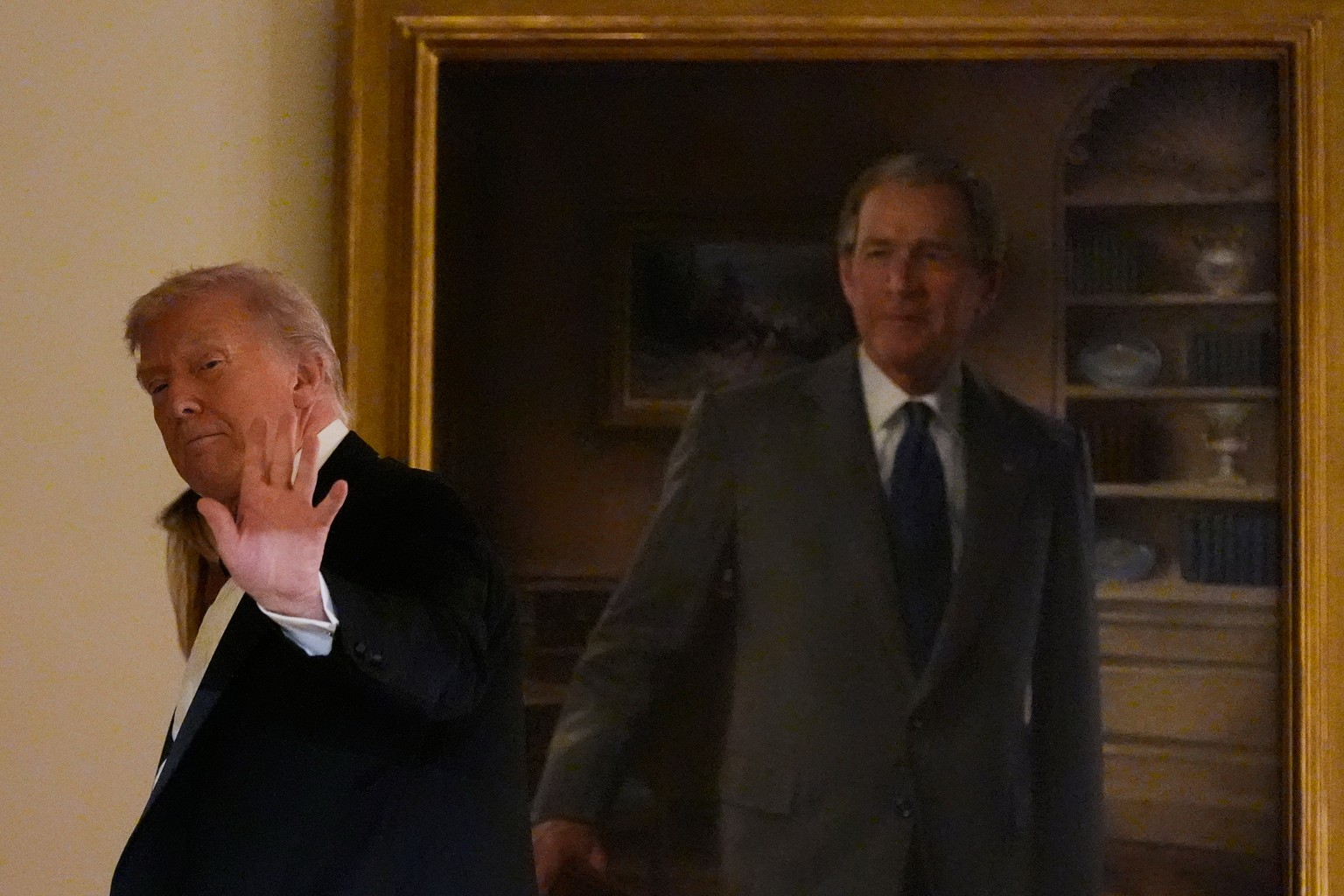President Donald Trump waves as he leaves passing a portrait of former President George W. Bush in the Grand Foyer of the White House during the Congressional Ball, Thursday, Dec. 11, 2025, in Washing ...