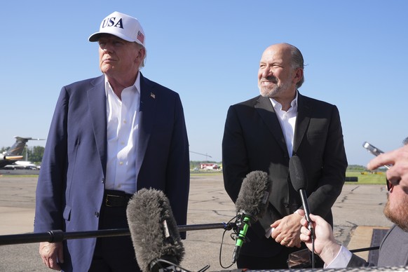 President Donald Trump, left, listens as Commerce Secretary Howard Lutnick speaks with reporters before boarding Air Force One at Morristown Municipal Airport in Morristown, N.J., Sunday, July 6, 2025 ...