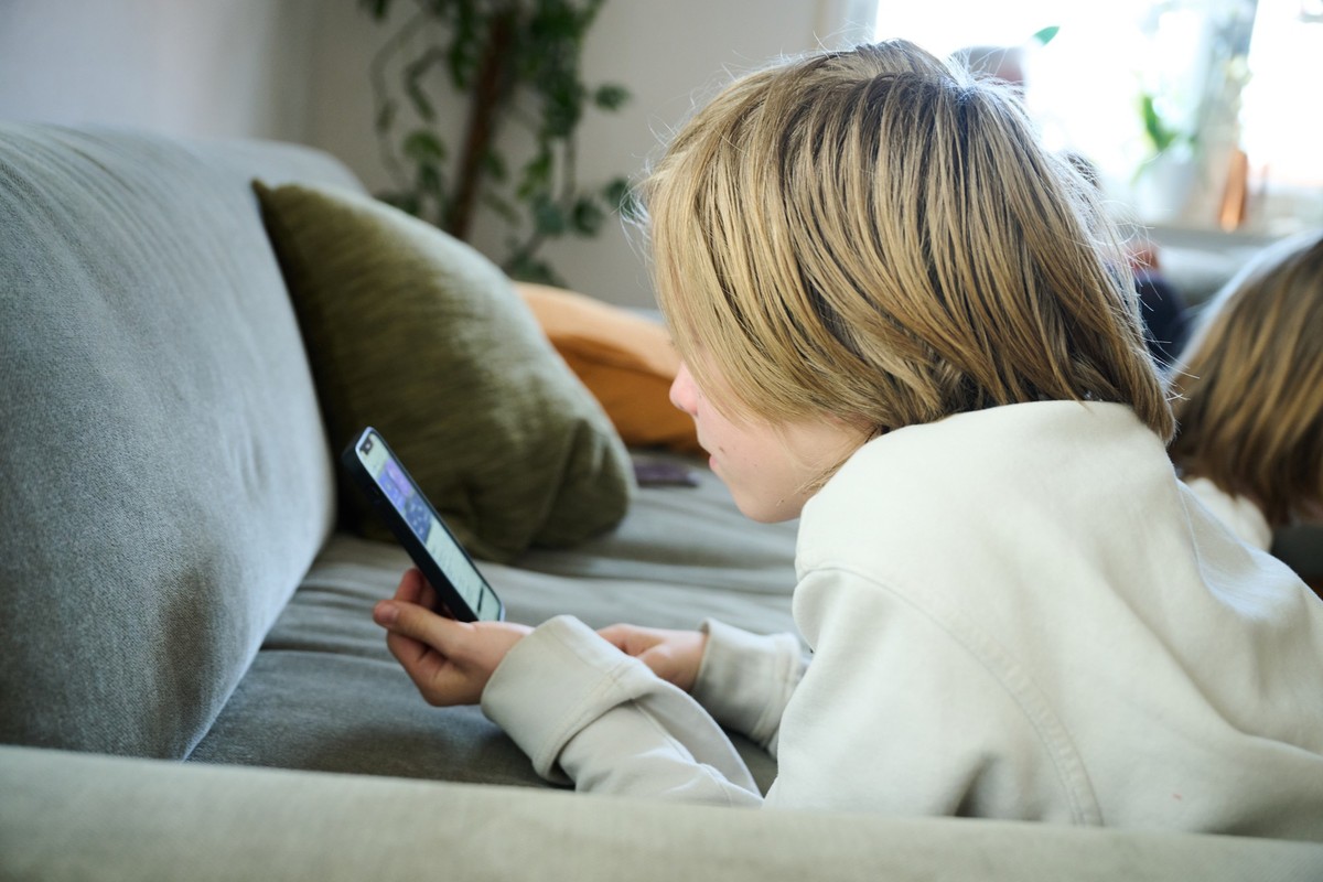 ARCHIV - 21.04.2025, Bayern, Roth: ILLUSTRATION - Ein Junge liegt auf einem Sofa und guckt auf sein Smartphone. (gestellte Szene). Kinder und Jugendliche verbringen immer fr