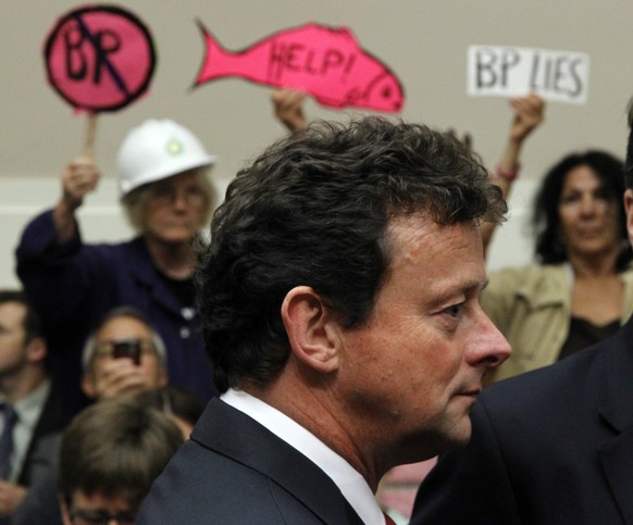 FILE - In this Thursday, June 17, 2010, file photo, protesters stand behind BP CEO Tony Hayward as he arrives on Capitol Hill in Washington, to testify before the House Oversight and Investigations su ...