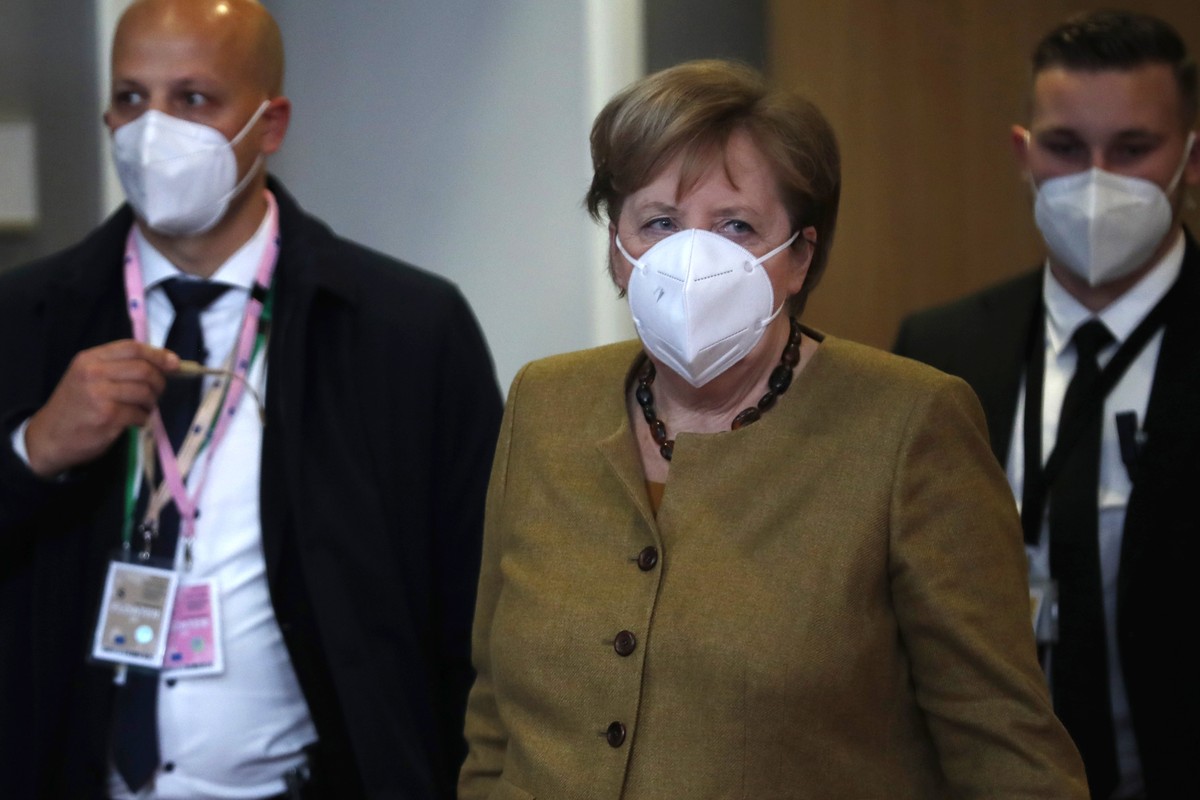 German Chancellor Angela Merkel, center, leaves at the end of an EU summit in Brussels, Friday, Dec. 11, 2020. European Union leaders have reached a hard-fought deal to cut the bloc's greenhouse  ...