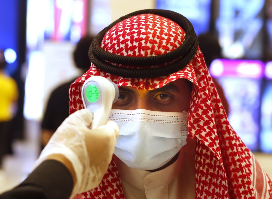 Vor dem Kinobesuch wird bei einem Mann in Saudi-Arabien die Temperatur gemessen. 