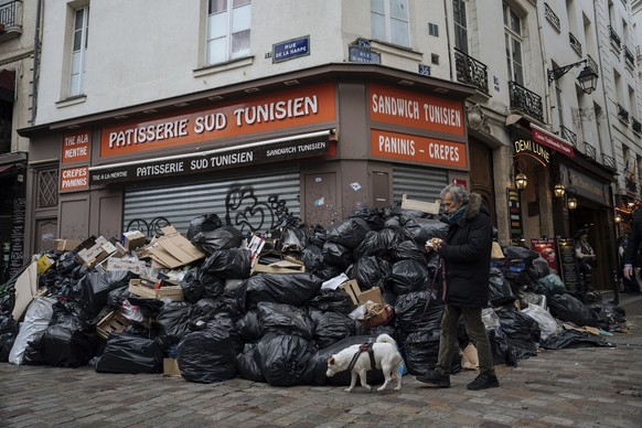 A man walks past piles of garbage in Paris, Monday, March 13, 2023. A contentious bill that would raise the retirement age in France from 62 to 64 got a push forward with the Senate&#039;s adoption of ...