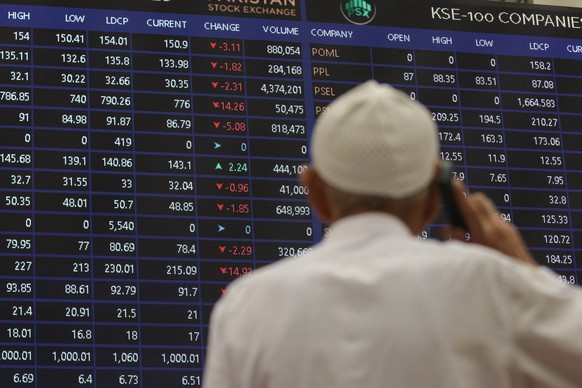 epa09806918 A Pakistani stockbroker talks on his mobile phone as he monitors share prices during a trading session at the Pakistan Stock Exchange (PSX) in Karachi, Pakistan, 07 March 2022. The Pakista ...