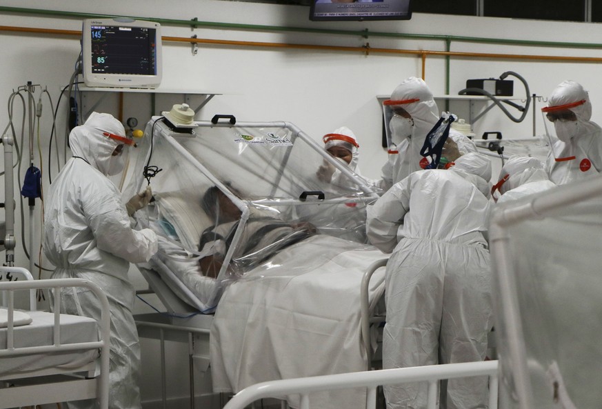 In this April 14, 2020 photo, health workers help a patient suffering from COVID-19 disease, inside the field municipal Hospital Gilberto Novaes, in Manaus, Brazil. Federal authorities have recognized ...