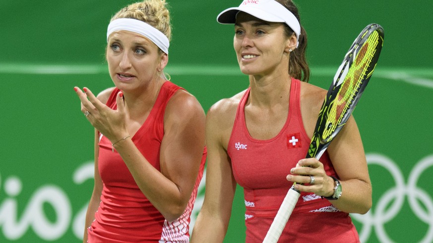 Timea Bacsinszky, left, speaks with Martina Hingis, right, of Switzerland during the womenÕs first round doubles match against Daria Gavrilova and Samantha Stosur from Australia at the Olympic Tennis  ...