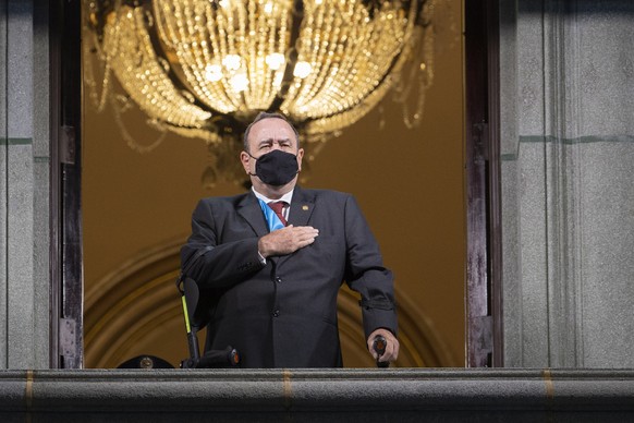 Guatemalan President Alejandro Giammattei wearing a protective face mask as a precaution against the spread of the new coronavirus sings the national anthem during the independence day celebration in  ...