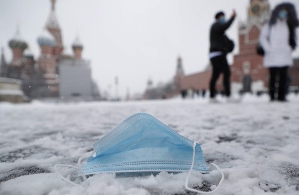 epa09627361 A discarded protective face mask lies on the Red Square outside the Kremlin after a snowfall in Moscow, Russia, 07 December 2021. Temperatures dropped to -1 degrees Celsius in Moscow, acco ...