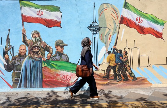 epa13023947 An Iranian woman walks past a mural on a street in Tehran, Iran, 08 June 2026. Iran and Israel exchanged fire after Iran launched missiles at Israel in retaliation for an earlier Israeli s ...