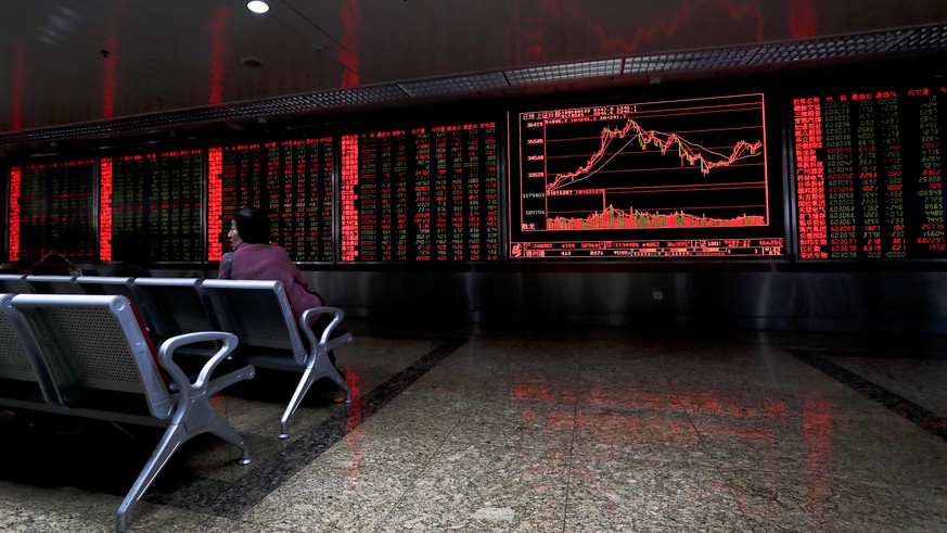 A woman looks back as she monitors stock prices at a brokerage house in Beijing, Monday, Jan. 22, 2018. Asian stock markets were mixed Monday after global investors shrugged off the latest U.S. govern ...