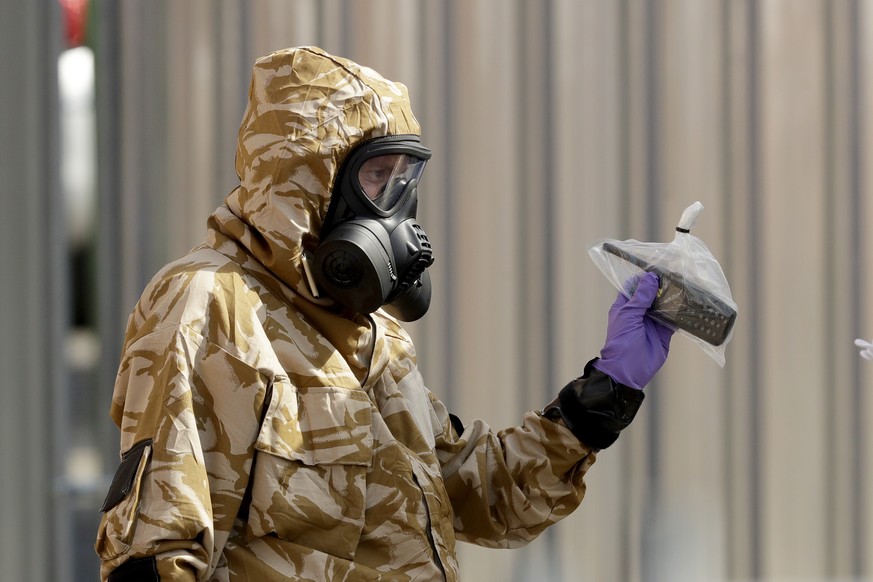 A specialist team member in a military protective suit leaves the front entrance of John Baker House for homeless people on Rollestone Street in Salisbury, England, Friday, July 6, 2018. British polic ...