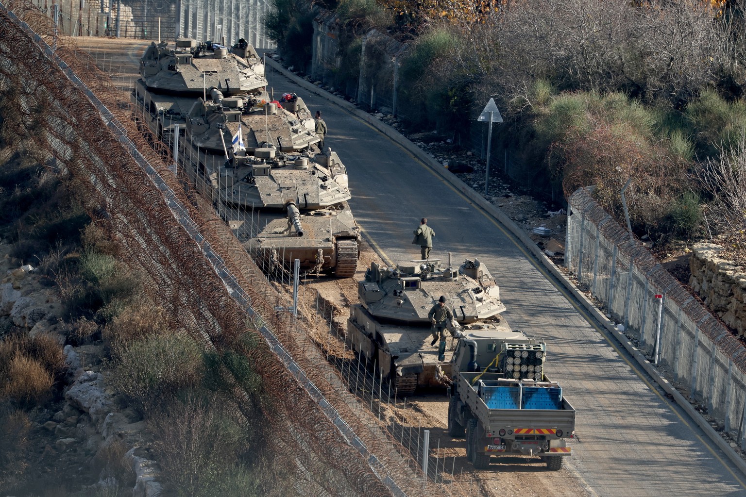 epa11764585 Israeli tanks deploy next to the security fence near the Druze village of Majdal Shams on Israel border with Syria in the Israeli-annexed Golan Heights, 08 December 2024. The Israeli army  ...
