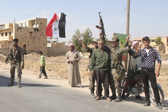 People welcome Syrian troops as they enter the village of Ghebesh, west of the town of Tal Tamr, in northern Syria, Monday, Oct 14, 2019. Syrian government troops moved into towns and villages in nort ...