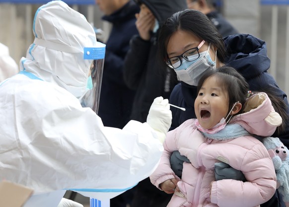 In this photo released by China&#039;s Xinhua News Agency, a worker in a protective suit takes a swab from a child for a coronavirus test in Shijiazhuang in northern China&#039;s Hebei Province, Monda ...