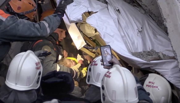 This photo provided by the Russian Emergency Situations Ministry taken from tv footage shows Emergency Situations employees save a 10 month old baby at the scene of a collapsed section of an apartment ...