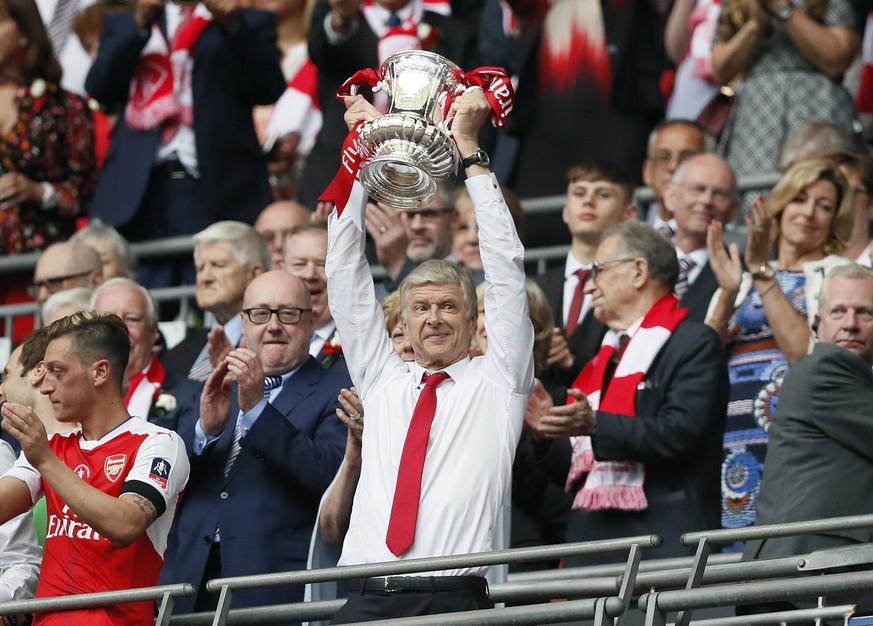 FILE - In this Saturday, May 27, 2017 file photo, Arsenal team manager Arsene Wenger celebrates with the trophy after winning the English FA Cup final soccer match between Arsenal and Chelsea at Wembl ...