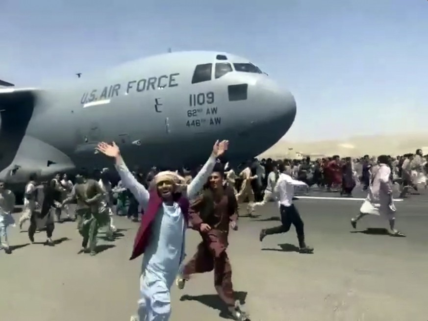 Hundreds of people run alongside a U.S. Air Force C-17 transport plane as it moves down a runway of the international airport, in Kabul, Afghanistan, Monday, Aug.16. 2021. Thousands of Afghans have ru ...