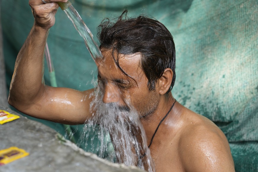A man bathes at a public water tap during a hot summer afternoon in Lucknow in the central Indian state of Uttar Pradesh, Thursday, April 28, 2022. Severe heat wave conditions are sweeping north and w ...