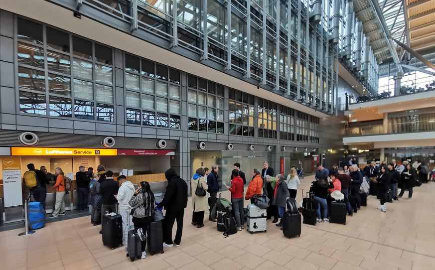 15.02.2023, Hamburg: Reisende warten an einem Serviceschalter der Lufthansa. Eine IT-Panne sorgt f