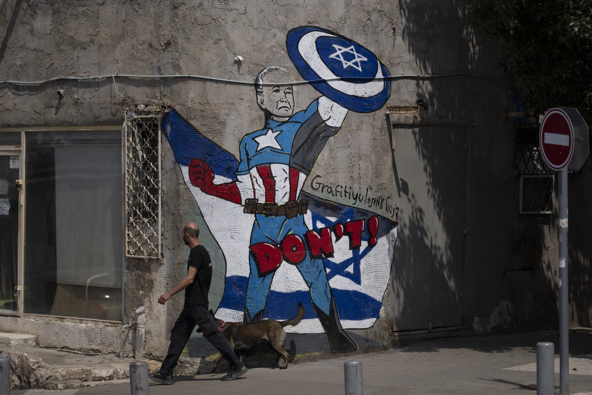 Un homme passe devant une fresque Joe Biden en super-héros défendant Israël dans une rue de Tel Aviv, Israël, dimanche 14 avril 2024.